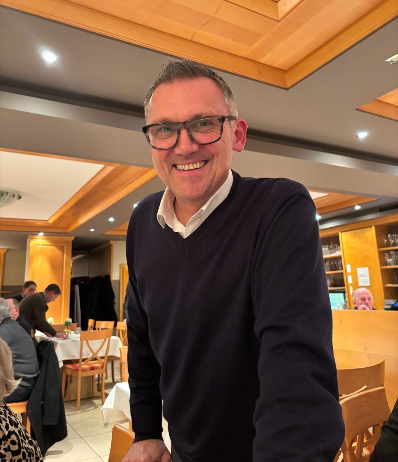 Ein lächelnder Mann (Ludwig Wahl, Bürgermeister) mit Brille in einem Restaurantambiente.
