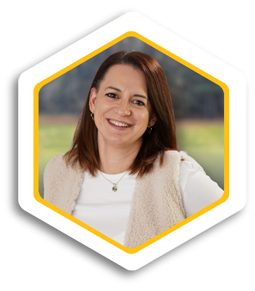 Frau mit langen, braunen Haaren und freundlichem Lächeln, in einem hellen Umfeld.